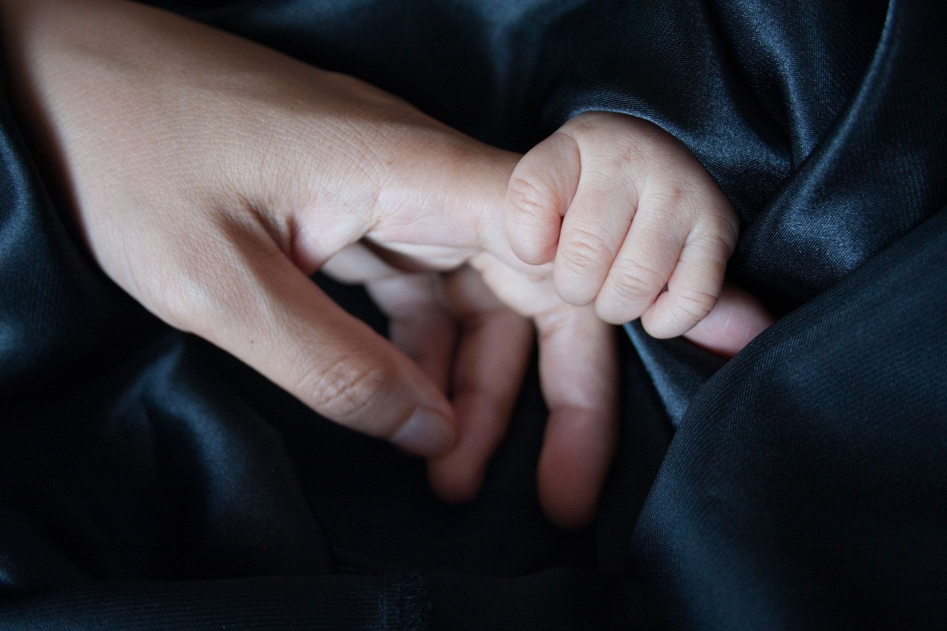 Photo of a baby holding a finger