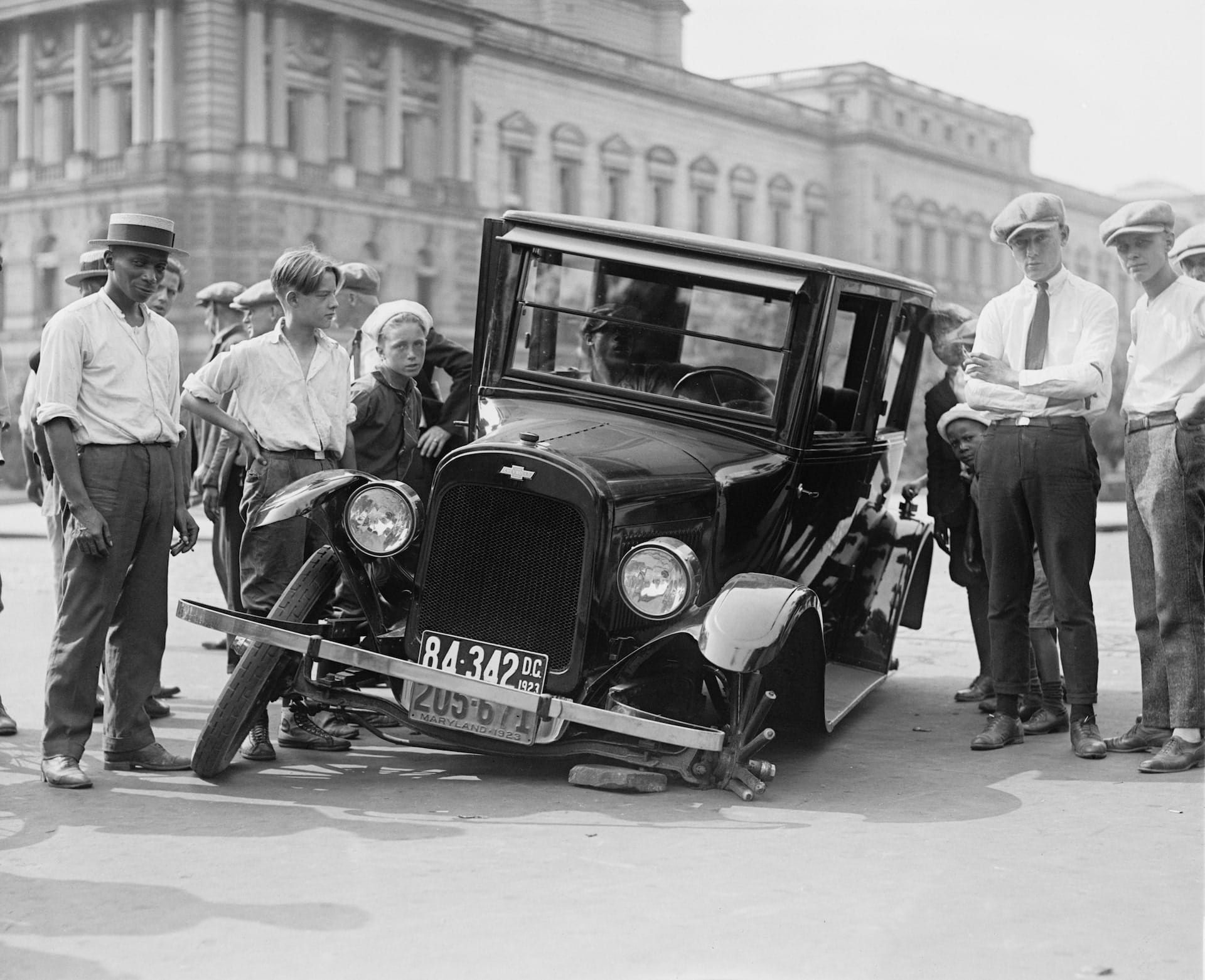 A photo showing a broken down car and a lot of people discussing it